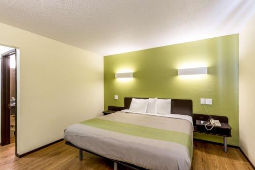 a bedroom with a large bed with a green wall at Motel 6-Troy, IL in Troy