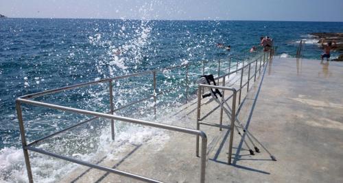 a pier with people swimming in the ocean at Apartments Hana in Pula