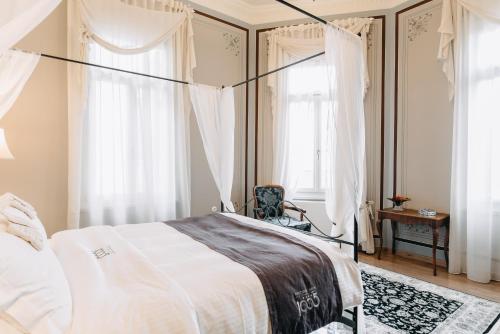 a bedroom with a bed and a chair and windows at Boutique Hotel 1905 in Xanthi