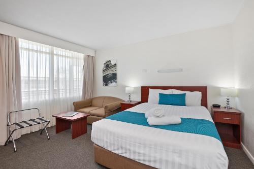 a hotel room with a large bed and a couch at Thunderbird Motel Yass in Yass