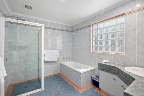 a bathroom with a tub and a sink and a shower at Thunderbird Motel Yass in Yass