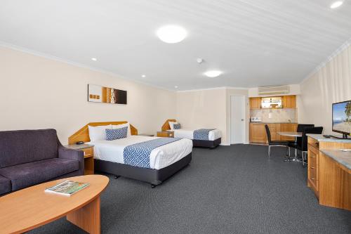 a hotel room with two beds a couch and a table at Thunderbird Motel Yass in Yass