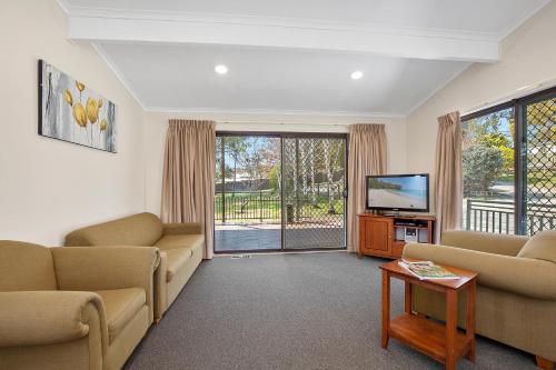 a living room with two couches and a television at Thunderbird Motel Yass in Yass