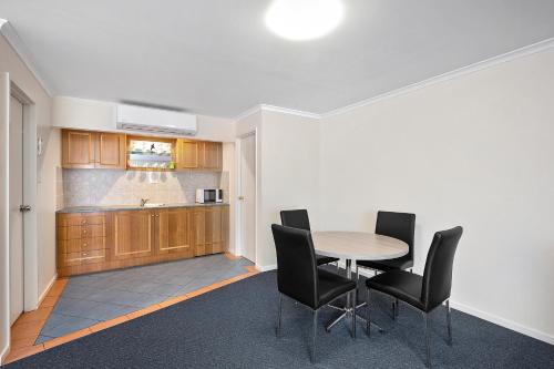 a kitchen with a table and black chairs at Thunderbird Motel Yass in Yass