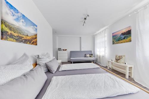 Una habitación blanca con dos camas y un sofá. en Wohnung 4 - nur 5 min vom Europapark, en Altdorf