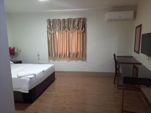 a bedroom with a bed and a desk and a window at Meaco Royal Hotel - Batangas City in Batangas City