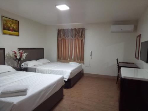 a hotel room with two beds and a window at Meaco Royal Hotel - Batangas City in Batangas City
