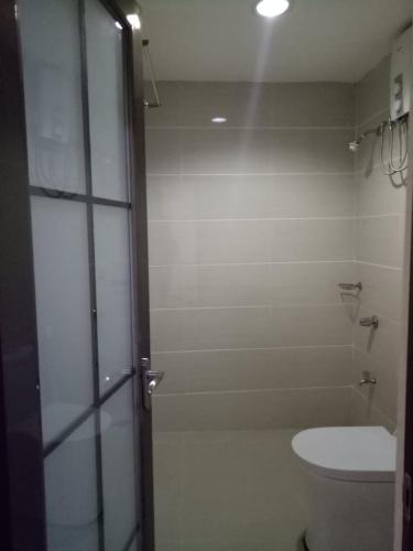 a bathroom with a toilet and a glass shower door at Meaco Royal Hotel - Batangas City in Batangas City