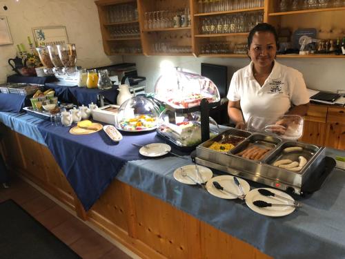 a woman standing in a kitchen preparing food at PAGA Hotel in Aidenbach