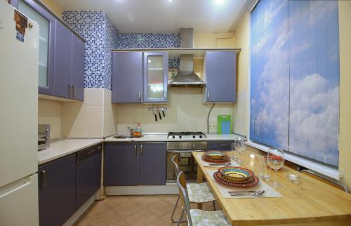 モスクワにあるHoliday Kutuzovskyのキッチン(紫色のキャビネット、木製テーブル、椅子付)