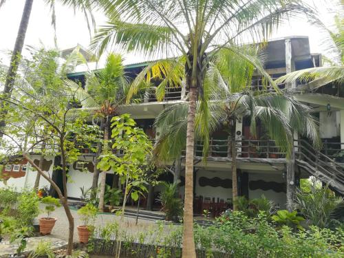 a building with palm trees in front of it at The Nature Park Villa in Sigiriya