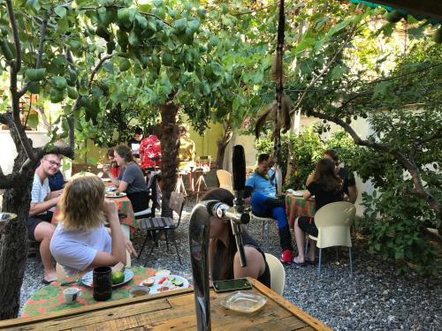 a group of people sitting at tables in a garden at Milingona City Center Hostel in Tirana
