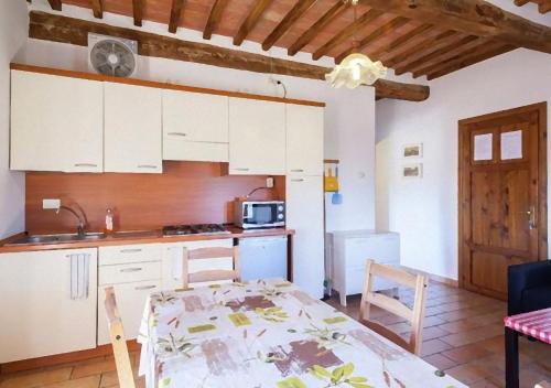 a kitchen with white cabinets and a table and a table and chairs at Lo Scricciolo in Montecastelli Pisano