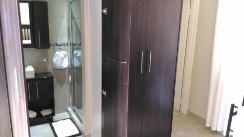 a bathroom with a shower and a brown cabinet at Protea Retreat in Brackenfell