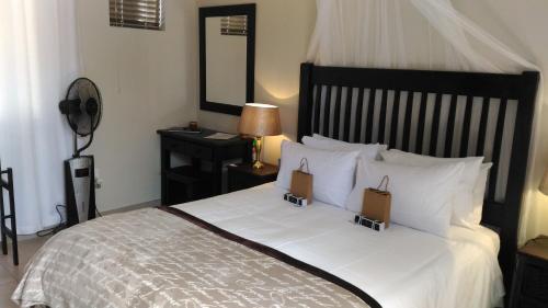 a bedroom with a large white bed with two bags on it at Protea Retreat in Brackenfell