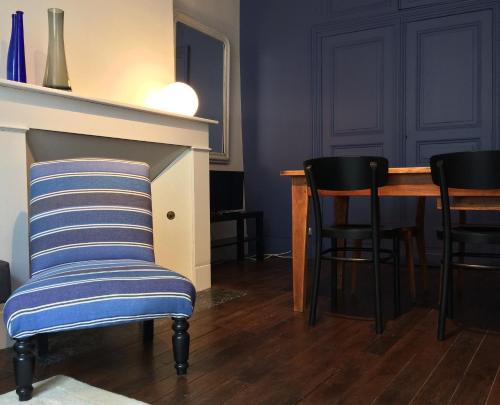 Cette chambre comprend une table, des chaises et un fauteuil rayé. dans l'établissement Sur la Route de Beauval, à Saint-Aignan