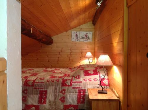 Un dormitorio con una cama y una mesa con una lámpara. en Le Chalet de La Pat, en Hauteluce