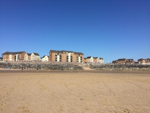 uma praia arenosa com casas ao fundo em Beach Break Aberavon Holiday Home by the Sea em Port Talbot