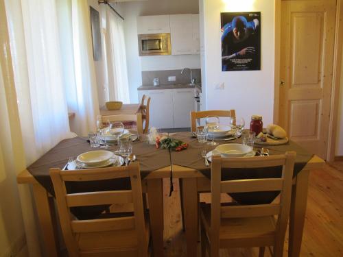 a dining room table with chairs and a wooden table with glasses at Il Cardo Trentino in Bedollo