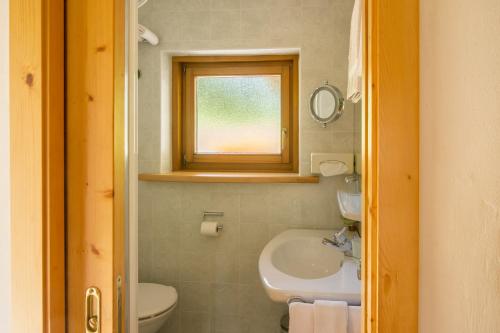 a bathroom with a sink and a toilet and a window at Villa Insam in Selva di Val Gardena