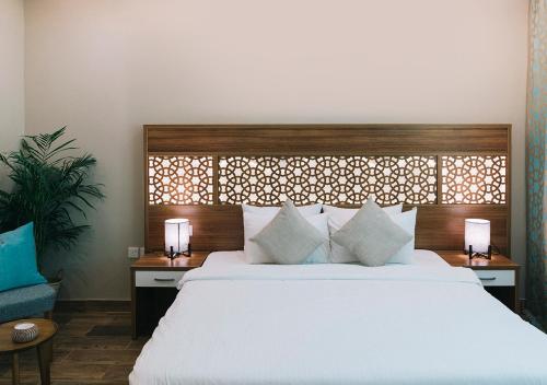 a bedroom with a large white bed with two lamps at فندق جمانة ينبع in Yanbu