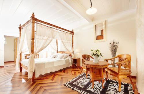 サラジーにあるRelais Des Gouverneursのベッドルーム(天蓋付きベッド1台、テーブル、椅子付)