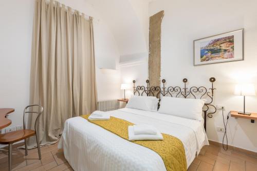 Apartment Via dei Benci في فلورنسا: غرفة نوم بسرير ابيض كبير عليها منشفتين
