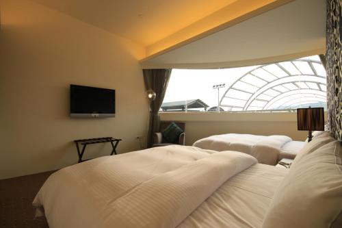 a hotel room with three beds and a flat screen tv at Mountain Fish Water Hotel in Jiji
