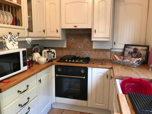 uma cozinha com armários brancos e um forno com placa de fogão em Southwell em Southwell
