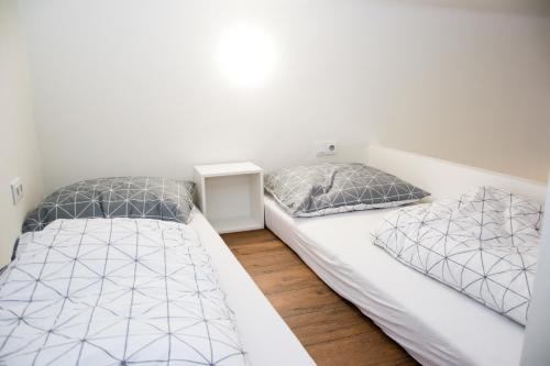 2 camas en un dormitorio con paredes blancas y suelo de madera en Sunny Aircon Apartment in the Centre of Slaný, en Slaný