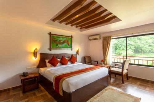 a hotel room with a bed and a large window at Landmark Forest Park in Sauraha