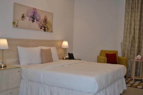 a hotel room with a white bed and two chairs at Sedra Residence in Kuwait