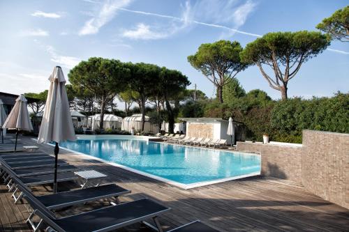 a swimming pool with lounge chairs and an umbrella at Villaggio La Pescaccia in San Clemente