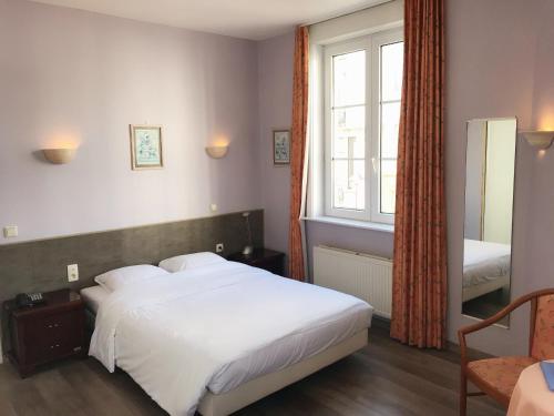 - une chambre avec un grand lit blanc et une fenêtre dans l'établissement Hotel Claridge, à Blankenberge