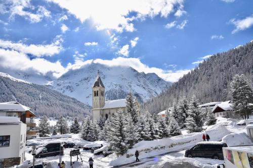 a snow covered town with a clock tower in front of a mountain at Bed & Breakfast Hotel Nives in Solda