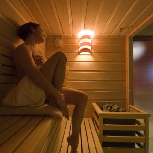 a woman sitting on a bed in a sauna at Hotel Du Lac - Relax Attitude Hotel in Brenzone sul Garda