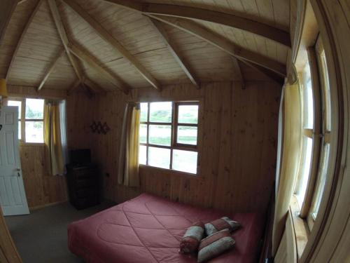 a bedroom with a bed in a room with windows at Hostal Guarida del Trauco in Puqueldón