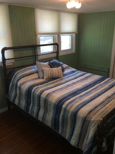 a bedroom with a bed with a striped blanket at A Day at the Lake Cottage in Colchester