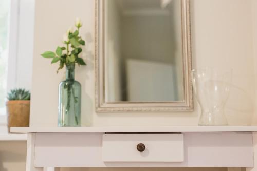 a white cabinet with a mirror and a vase on it at Dunna in Pápa