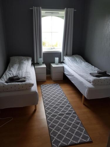 two beds in a room with a window and a rug at Solbakken 27 Apartment in Lyngseidet