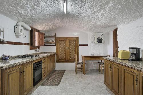 cocina con armarios de madera y encimera en Cueva Solano, en Gorafe