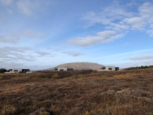 a group of houses in a field with a mountain in the background at Kerbyggd: Luxury house and cottage in golden circle in Selfoss