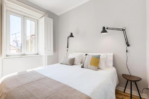 ein weißes Schlafzimmer mit einem Bett und einem Fenster in der Unterkunft Charming Apartment Rua da Rosa 33 in Lissabon