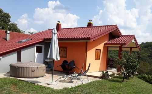 ein kleines Haus mit einem Regenschirm, einem Tisch und Stühlen in der Unterkunft Kuća za odmor "Nedeljko"/ Holliday hause "Nedeljko" in Sveti Martin na Muri