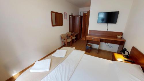 a room with two beds and a desk and a television at Noclegi Czarna Perła in Kraków