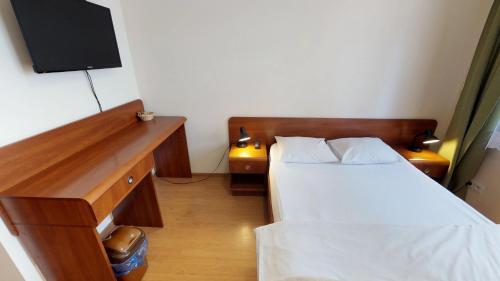 a bedroom with two beds and a desk with a television at Noclegi Czarna Perła in Kraków