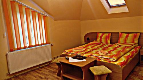 Schlafzimmer mit einem Bett, einem Tisch und einem Fenster in der Unterkunft Picnic Panzio in Lunca de Sus