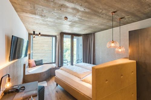 a bedroom with a bed and a tub and a sink at Seehotel Einwaller - adults only in Pertisau