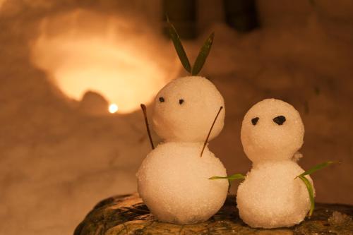two snowmen sitting on a rock with a fire in the background at Shosenkaku Kagetsu in Yuzawa