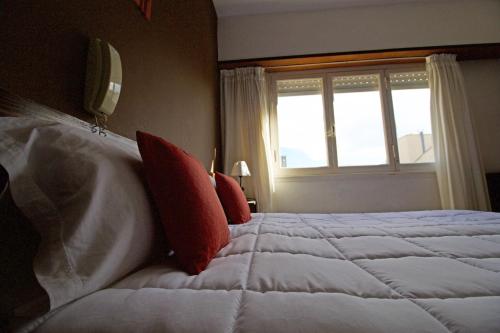 a bedroom with a large bed with red pillows and a window at Hotel Santa Eulalia II in Miramar